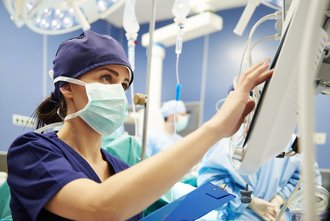 Eine Krankneschwester überprüft im Operationssaal am Monitor die Werte eines Patienten.