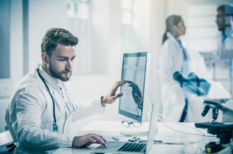 Ein Arzt betrachtet Patientendaten auf seinem Computer.