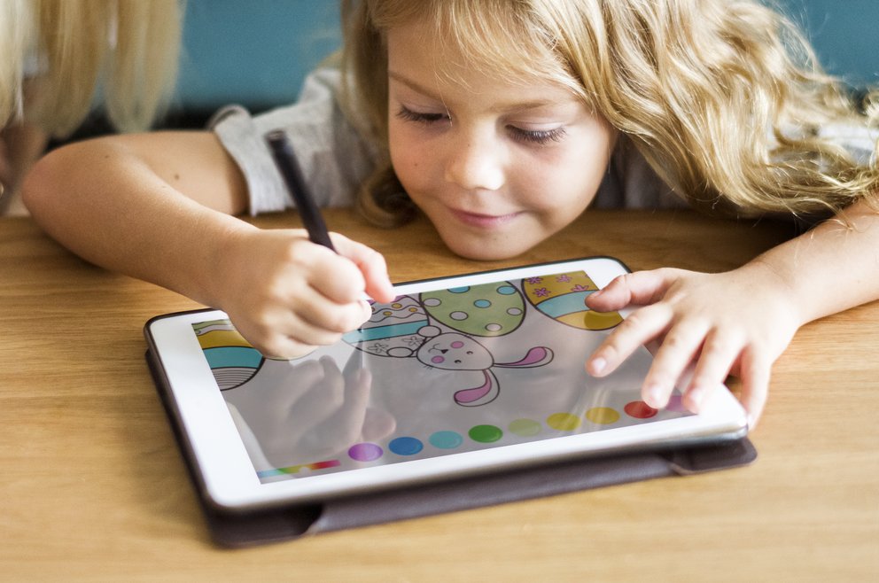 Ein Mädchen zeichnet mit einem Stift auf seinem Tablet.